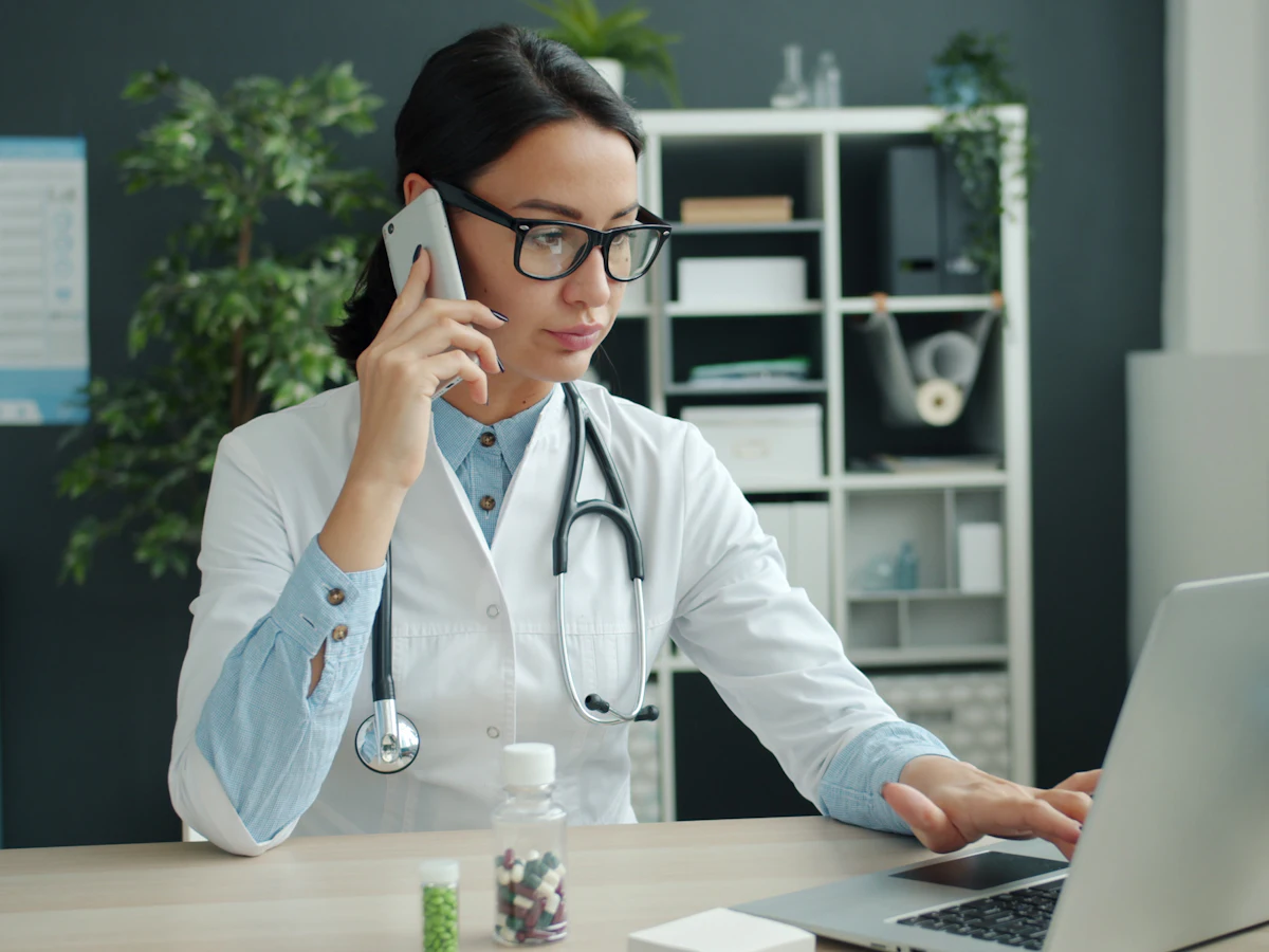 Médico hablando por teléfono en su consulta